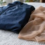 Donkerblauw nylon jack met waterdruppels naast een dunne nylon panty